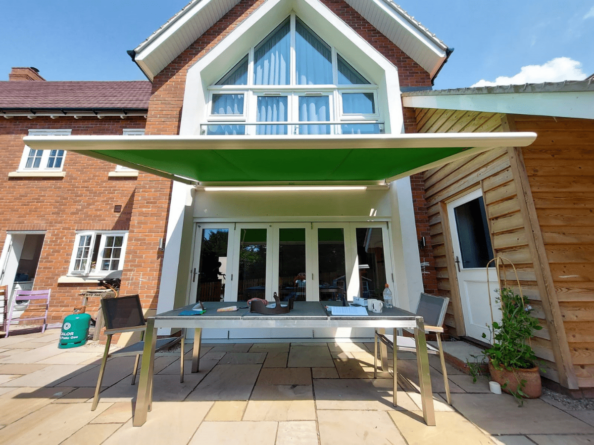 weinor Cassita II electric canopy in green with a light coloured cassette, sheltering a patio