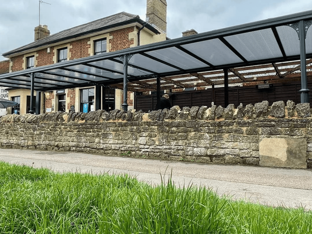 The Milwood Simplicity 16 roof with 16mm polycarbonate panels adds a modern and sleek look to a pub in Oxfordshire, providing an attractive and durable shelter for outdoor dining and entertainment.