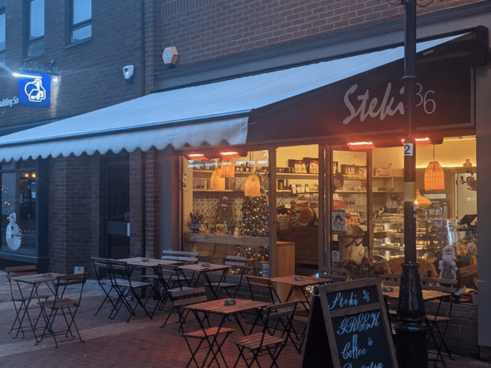 The Weinor Topas awning in RAL 9005 adds a touch of style to the outdoor seating area at Steki 36 Cafe in Rugby, featuring a 5.3m width and 4m projection, as well as a convenient wind sensor and remote control for easy operation.
