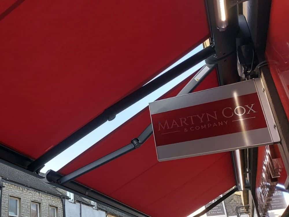 weinor Cassita II coupled awning outside an estate agents in Witney, Oxfordshire colour matched to shop sign. With remote control and wind sensors.