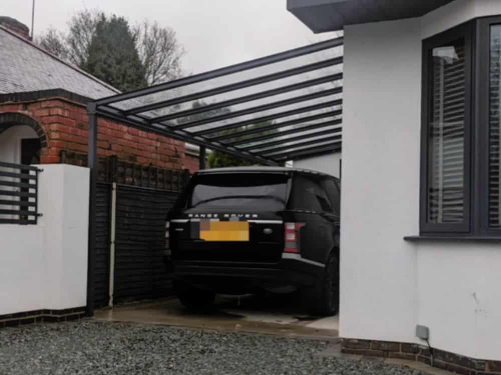 Milwood Simplicity 16 polycarbonate roof with supporting posts fitted to the side of a house in Warwickshire to shelter the owner's vehicles