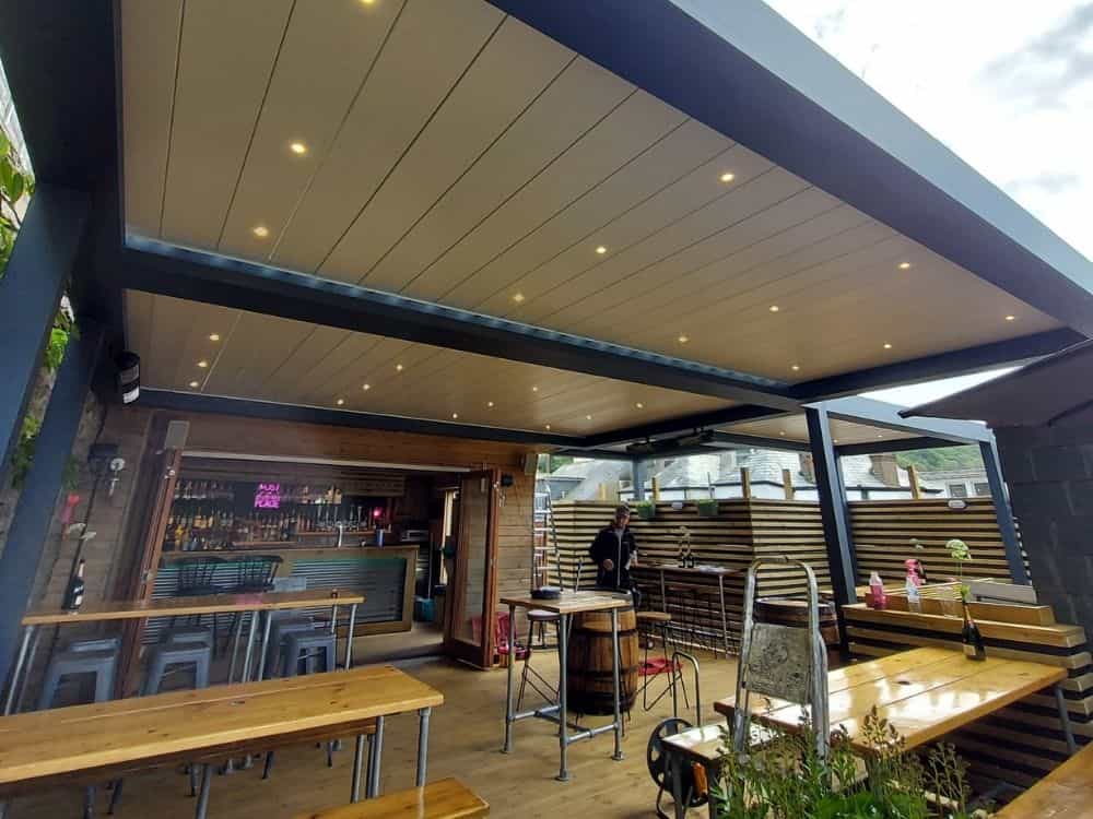 Discover the impressive installation of four Tarasola Technic louvred roofs integrated into one structure at the Golden Guinea Pub in Cornwall, providing a versatile and functional outdoor space.