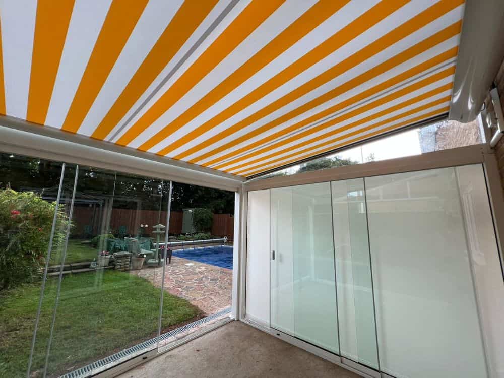 Weinor Terrazza Sempra glass room installed at the back of a house in Bristol, featuring remote-controlled underawning, LED spotlights in two roof bars, and glass sliding doors. The glass room offers an elegant and functional outdoor living space, with a clear view of the surroundings.