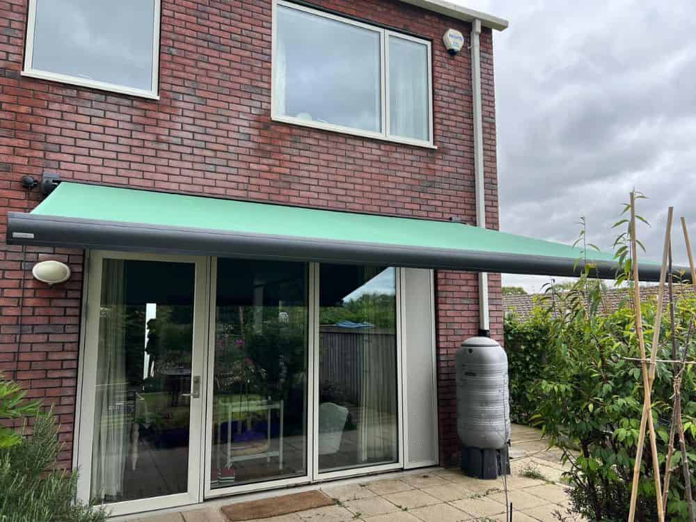 The Markilux MX-3 awning fixed to the back of a house in Stroud, Gloucestershire, provides the perfect upgrade to your backyard living space, featuring a 4.5m x 3m projection, remote control, wind sensor, and LED lights fitted under the cassette, allowing for an enjoyable and convenient outdoor living experience.