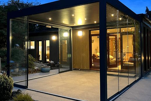 The Tarasola Technic glass room in Derbyshire features a louvred roof and glass sliding sides, allowing for easy access from outside and providing a comfortable outdoor living space all year round thanks to integrated LED lights and infrared heater.