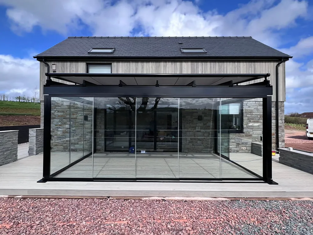 Glass room with over awning for outdoor relaxation by Cotswold Awnings and Pergolas