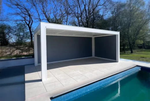 Front view of the installed KE Kedry Prime louvred roof pergola with the swimming pool in the background and the zip screens down, offering a private and cozy outdoor area.